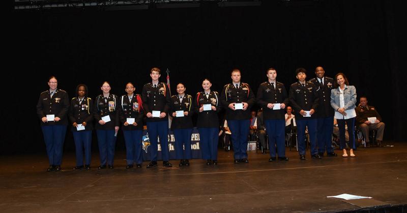 Sgt. First Class Richard Hurt and Ava Cannon present the Dewey Beach Triathlon Scholarship to cadets Jenna Calhoun, Kamille Glenn, Rylee Tipton, Jazmine Ramos-Trejo, Liam Drevno, Ady Ramirez, Gianna Decker, Brent Dieterle, Michael Pond and Guilmer Ramirez-Chilel.