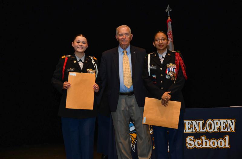 Sgt. Maj. (Ret.) Tom Blakely presents the Fort Miles Historical Association Scholarship to cadets Gianna Decker, left, and Jazmine Ramos-Trejo.
