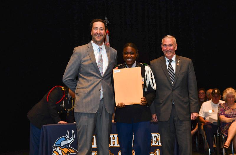 Maj. Gen. Fran Mahon and Andrew Coulter present the JROTC Perfect Attendance Medal to cadet Cianna Steer.