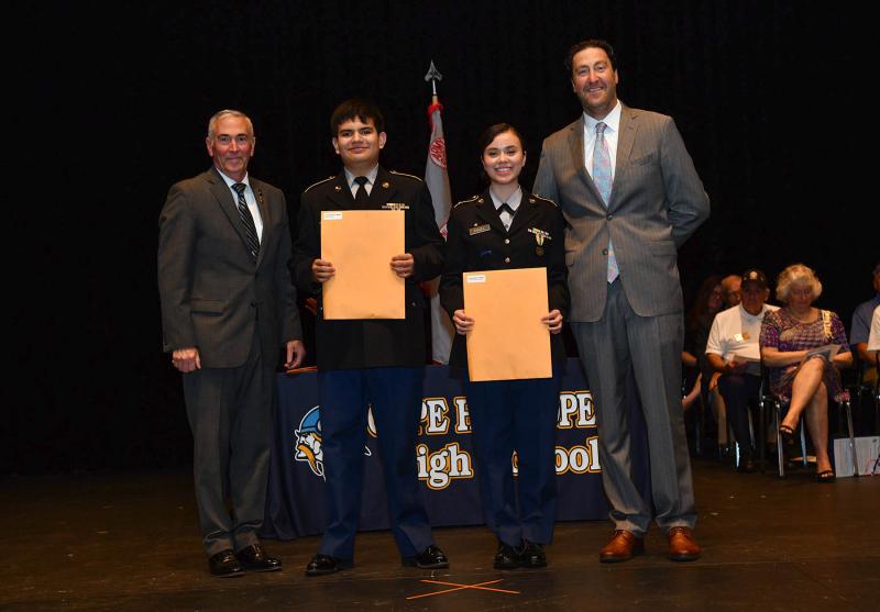 Maj. Gen. Fran Mahon and Andrew Coulter present the JROTC Commendation Medal to cadets Gabriel Meza and Claudia Mendoza Angel.