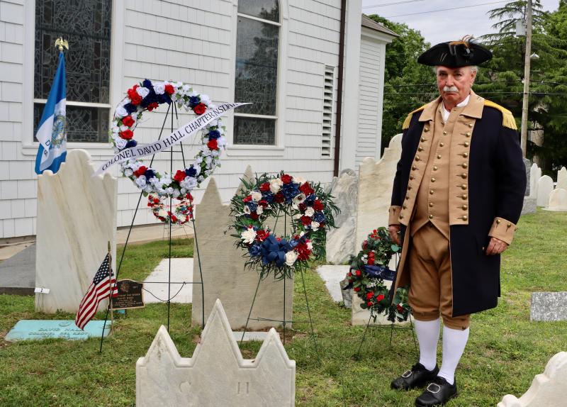 Allen Greenly, treasurer general of the National Society of the Sons of the American Revolution, lays a wreath on the grave of Col. David Hall. Greenly wears a traditional Revolutionary War-era uniform.