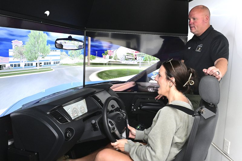 Madison Sapp tries the DUI simulator as Cpl. Keith Shyers, the DUI simulator coordinator with the Delaware Alcohol Enforcement, provides guidance.