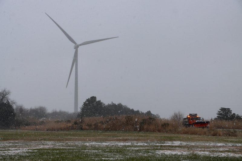 A DelDOT plow passes by the wind turbine on Park Road in Lewes during the season’s first snow fall Dec. 5. The snow coated lawns, cars and some roads. BILL SHULL PHOTO