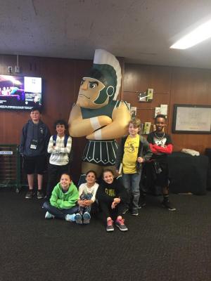 Shields Odyssey of the Mind team members pose with the Michigan Spartan at the world competition. Shown are (l-r)  DJ Schulze, Luca Miller, Bryna Conley, Avary Miller, Reese Petterson, Aidan Wiggins and  KJ Gibbs.