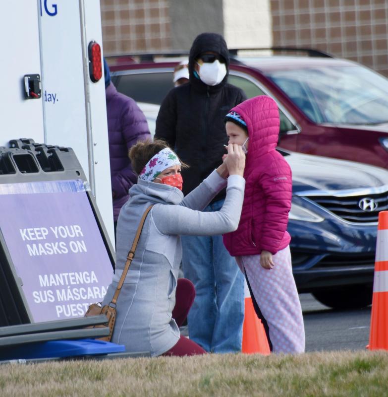 A mother swabs the mouth of one of her children at the Dec. 22 pop-up COVID-19 test site at Epworth UM Church.