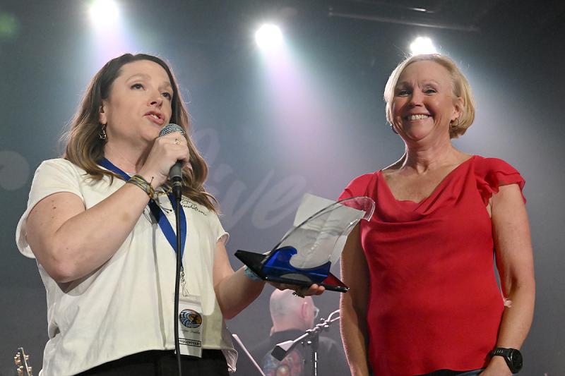 Melanie Liesener, president of the Surfgimp Foundation, presents Mary Beth Hutton with an award for her generosity.
