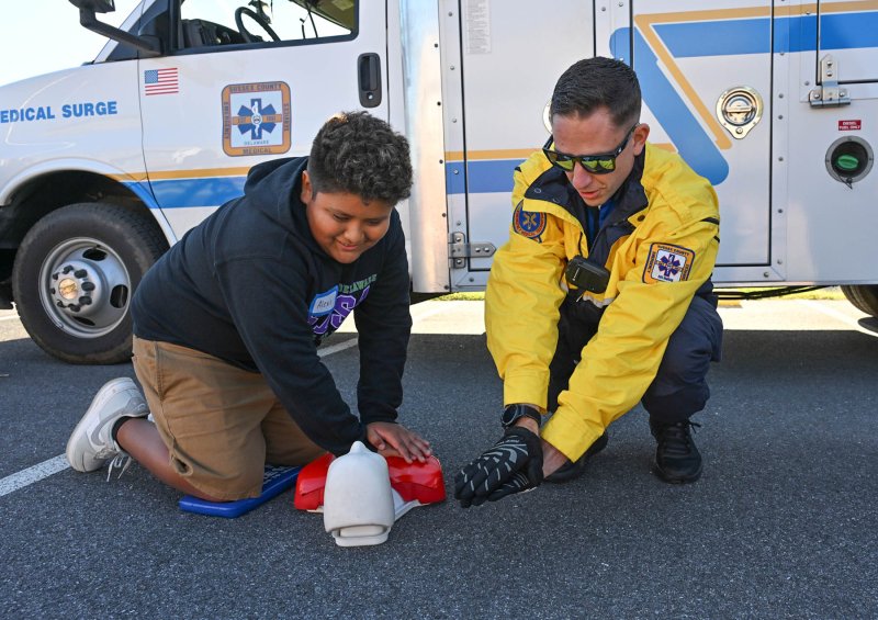 Fifth-grader Alexis Perez gets a CPR lesson from paramedic Austen Kauffman.