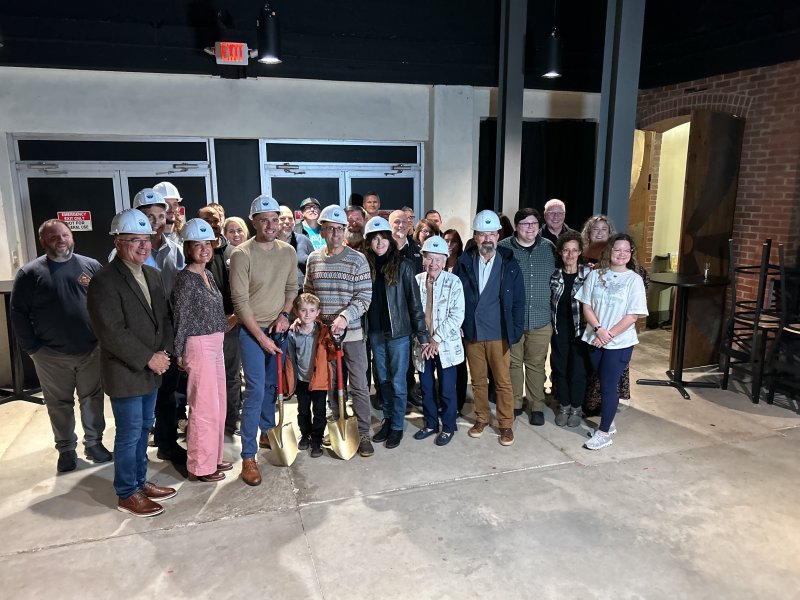 Officials and supporters of Milton Theatre gather to “break ground” on the new education wing, despite cold, windy and rainy weather outside.