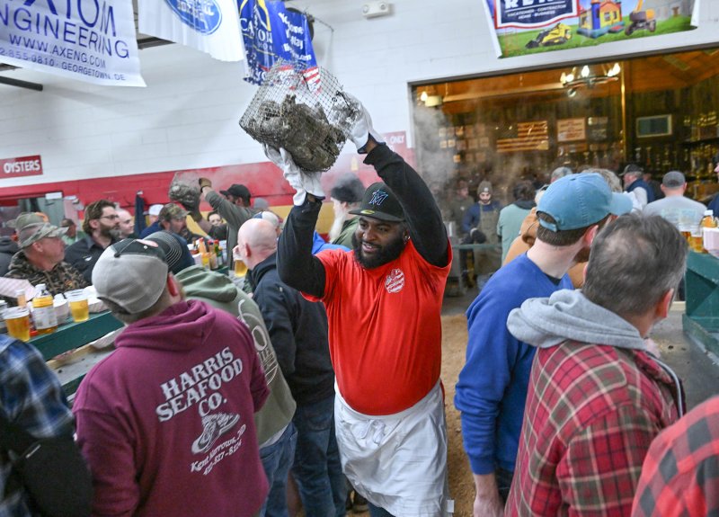 Georgetown firefighter Steven Norwood carries a basket of steaming saltwater bivalve mollusks.