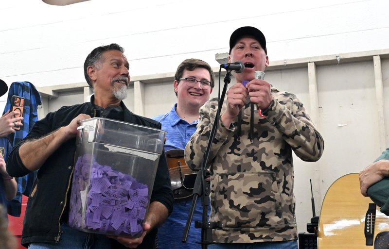 Michael Briggs, president of the Georgetown Fire Company and event chair, reads off the name of the 50/50 winner as Steve Smyk assists and Ryan Paisley, center, looks on.