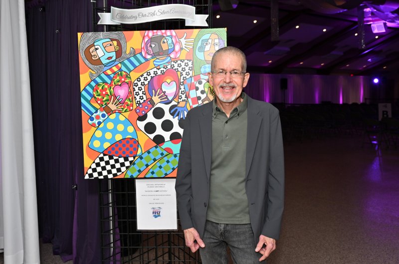 CAMP Rehoboth founder Murray Archabald stands with his painting that was auctioned off at the event.