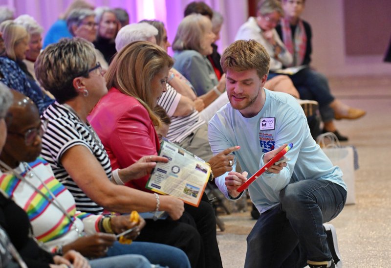 CAMP Rehoboth Communications Manager Matty Brown, right, takes a winning bid from Suzanne Krupa.
