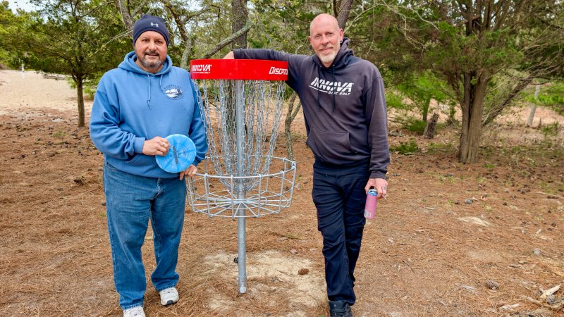Chris ‘Eagle” Peters, right, spent $3,855 of his own money to purchase new red baskets for the disc golf course at Cape Henlopen State Park, creating more options for experienced players like Miguel Garces, and increasing the accessibility of the game to all ages and skill levels. AARON R. MUSHRUSH PHOTOS