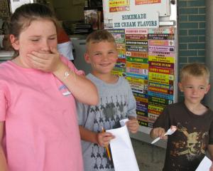 Aidan Crossan giggles as Alicia Strack takes a big bite of The Ice Cream Store's hottest new flavor, Scorpion Sting. They are joined by Idran Crossan, right.