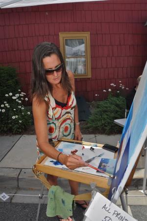 Featured artist Kim Klabe of Rehoboth Beach works on a painting during St. Peter’s 45th annual art show. BY RON MACARTHUR