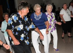 DJ Sky Brady leads Carol Hutson, center, and Elise Purchase in the Electric Slide. Brady kept the luncheon hopping with his mixture of rock 'n' roll and contemporary tunes.