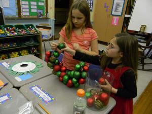 Kaitlyn Kachnovitz, left, and Sommer Dorman carefully thread ornaments onto a wreath. SOURCE SUBMITTED