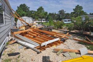 A section of torn-off roof leans up against a neighboring house. The flying debris damaged a boat parked in the driveway. BY RON MACARTHUR