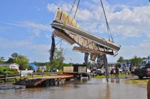 Remains of a pontoon boat are lifted out of the Pot Nets Bayside marina. BY RON MACARTHUR