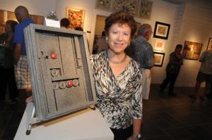 Jane Knaus stands with her mixed media assemblage “Ode to Louise III.” Knaus was inspired by the late Louise Nevelson, honoring her memory with a wooden monochromatic wall piece. BY STEVEN BILLUPS
