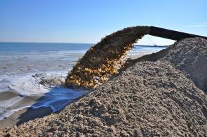 Sand flows from a pipe nonstop during the day onto a sand-starved beach on the north side of the inlet. BY RON MACARTHUR