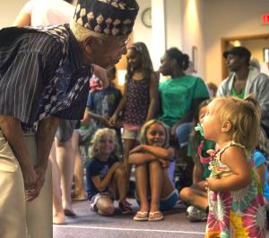 Ninety-year-old Reuben Salters asks Arilyn Staggs, 1, to dance during the audience participation portion of the Sankofa African dance & drum performance. BY DENY HOWETH