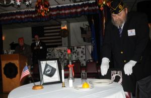 Sergeant at Arms Jerry Martin displays the single empty chair signifying the MIAs that cannot be with us because of their sacrifice as Marine veteran Austin Govin reads  the humble tribute. BY DAN COOK
