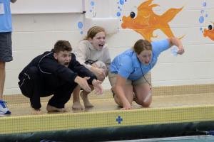 Cheering poolside are (l-r) Jack Weeks, Amelia Nigh-Johnson and assistant coach Kristina Lingo as Charlie Burton wins the individual medley in 2:30.09. BY DAN COOK