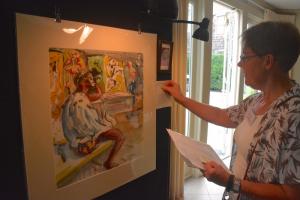 Candace Vessella, president of the Friends of the Lewes Public Library, places a sold tag on a Howard Schroeder painting. BY RON MACARTHUR