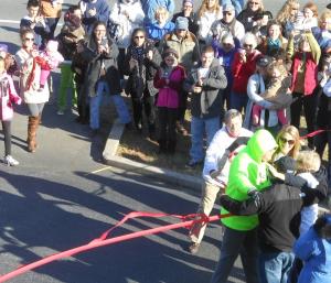 Surrounded by more than 100 supporters, Hill receives a big embrace from his wife Cindy, daughter Mary and friend Mario Aguillon as he crosses the finish line. BY CHRIS FLOOD