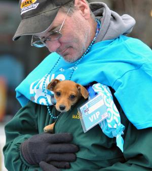 David Coulbourn keeps Nova the dachshund warm while they sign up for the cute pup award. BY DENY HOWETH