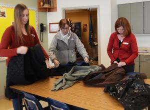 Kelly Lebbedz, Sheila Sweeney and Jen Jarrell fold and inspect coats that were donated. BY DENY HOWETH