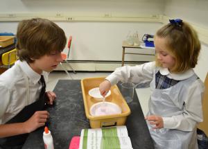 Worcester Prep sophomore Jonathan Ruddo of Berlin, Md., guides kindergartner Anna Mumford of Fenwick Island through directions for creation of slime.