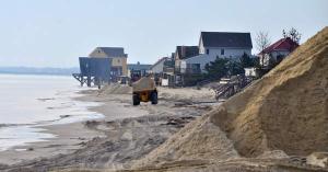 A truck hauls sand in front of houses along the Broadkill Beach duneline. There isn't much beach left in front of the Delaware Bay community. BY RON MACARTHUR