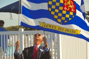 Rear Commodore Bert Keller raises the Lewes flag during the opening-day ceremony. BY RON MACARTHUR