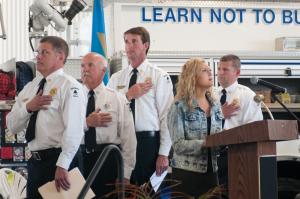 Lily McDaniel sings the national anthem to open the dedication, as (l-r) Chaplain Ralph Karl, Warren Jones, President Ronnie Blizzard and Chief Chatham Marsch raise their hands to their hearts. BY DENY HOWETH