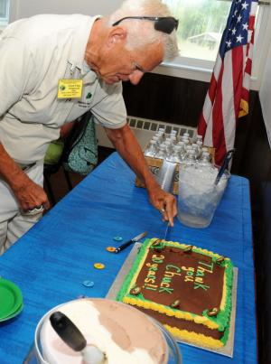 O'Day gets the first slice of cake honoring his 20 years of volunteer service. BY DAN COOK