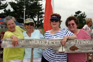 Kathy Lock, left, and some friends pose for a photo with the regatta sign on the Fourth of July. BY BECKY CRAFT
