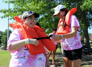 SODE athlete Beth Lints, left, gets assistance with her life vest from counselor Mary Getty. Kayaking and canoeing are popular activities at the camp. BY DAN COOK