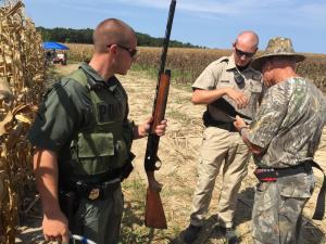 Fish and Wildlife Officers Adam Roark, left, and Travis Anderson check the gun, license and permits of Ron Sams in a Broadkill-area dove field. BY DENNIS FORNEY