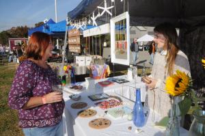 Cindy Brought, left, talks about the jewelry available in the Seaglass Jewelry booth made by Emily Rathmann from Hockessin. BY STEVEN BILLUPS