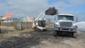 Following the storm, a Department of Natural Resources and Environmental Control crew works to remove fencing in Rehoboth Beach. BY RON MACARTHUR