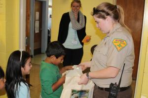Gabriel Hildago checks out his gift bag from Forester Laura Yowell. Jeleiny Gutierrez waits her turn and teacher Anita Hawkins watches. BY MELISSA STEELE