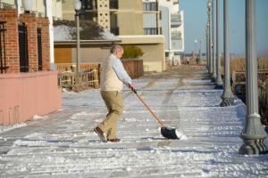 Steve Griffith – known as Moose – shovels snow and sand off the Boardwalk in front of Boardwalk Plaza. BY RON MACARTHUR