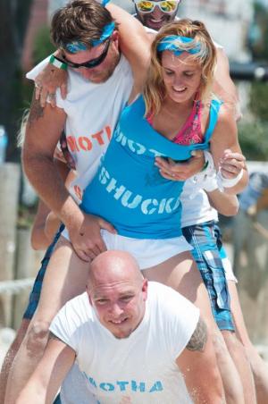 Ian Wood busts through the leg crawl for his chance to do the dizzy bat race, Jon Murray holds Ashley Murray after her dizzying race.