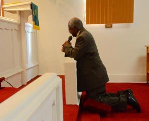 Bruce Duffy of Faith United Methodist Church kneels in prayer as he offers the invocation.