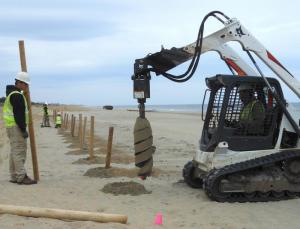 Charlie Black pulls out a drill bit’s worth of sand while Levi Rolles gets ready to put in the 8-foot-tall post. CHRIS FLOOD PHOTO