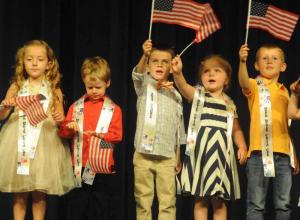 Waving American flags as they sing “Proud to be an American” are Lyric Hudson, Ethan Jensen, Daxton Napolitano, Lily Peltz and Gavin Serman from the Rehoboth Campus.