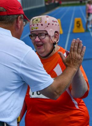 Laurie Bainbridge is met at the finish by a volunteer after completing the 100-yard walk competition. Nearly 75 athletes competed in the track & field program. DAN COOK PHOTO