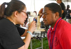 Sussex Riptide athlete Reggie Miller gets his eyes checked by volunteer Linen Pok at the Opening Eyes tent at Olympic Village. DAN COOK PHOTO